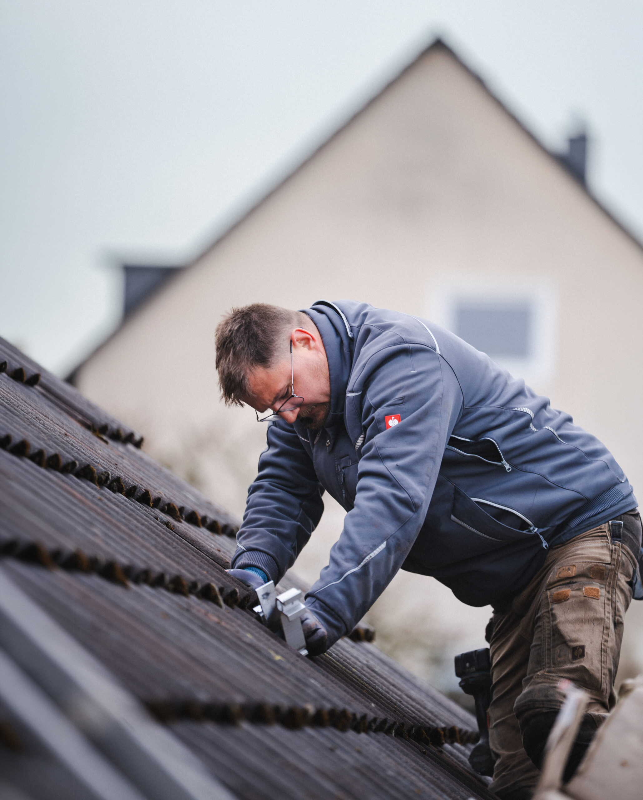 Mitarbeiter der MMS GmbH montiert eine Halterung für eine Photovoltaikanlage auf einem Ziegeldach.